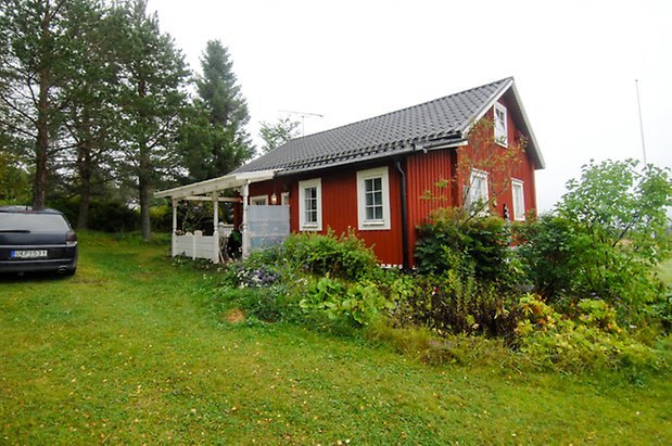 Västanede 2:5. Hus i röd panel med veranda med vit snickarglädje, fönster med spröjs.