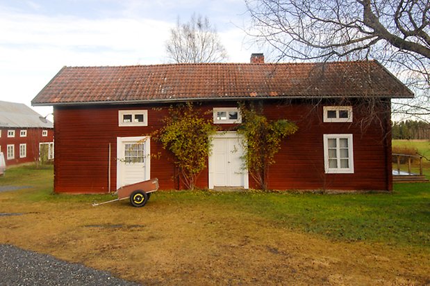 Fugelsta 2:65. Hus i rött timmer i två våningar med vit dubbeldörr, vit dörr och fönster med vita spröjs.