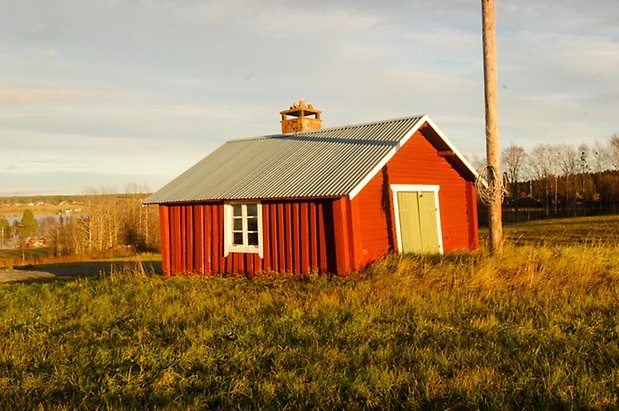 Öd 2:17. Byggnad i timmer och panel, med grön dubbelport och ett fönster med vitt spröjs, tegelskorsten.