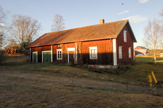 Överbyn 1:11. Byggnad i två våningar i röd panel och timmer, brun dubbeldörr, fönster med vita spröjs, grön dubbelport och port.