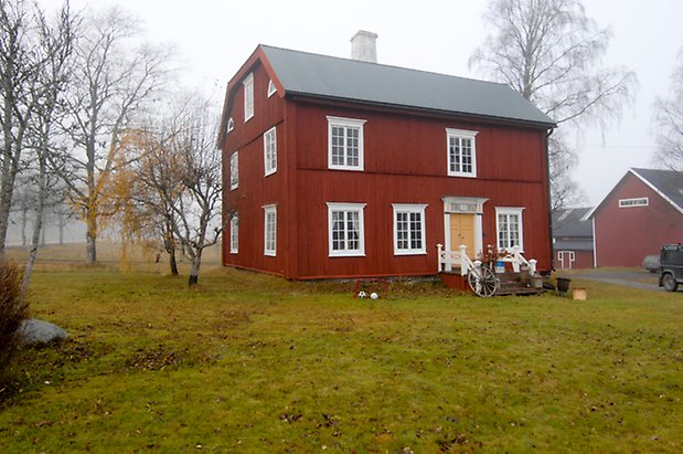 Lungre 1:2. Hus i tre våningar i röd panel, trapp med vitt staket, gul dubbeldörr, fönster med vita spröjs och skorsten i vit puts.