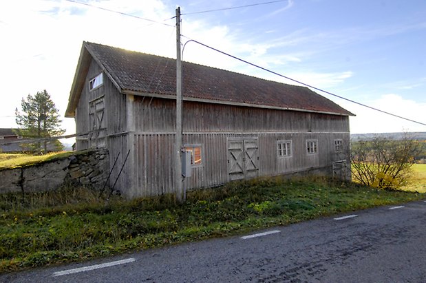 Österåsen 9:23. Ladugård i grå panel, tre grå dubbelportar, fönster med spröjs.