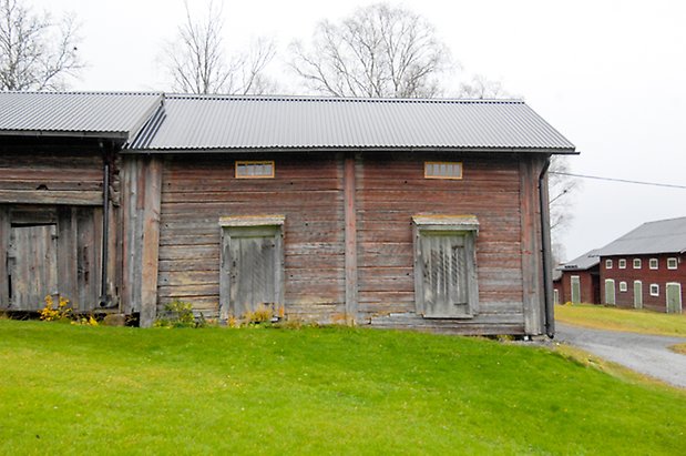 Backegård 1:23. Byggnad i rött/grått timmer med två grå portar.