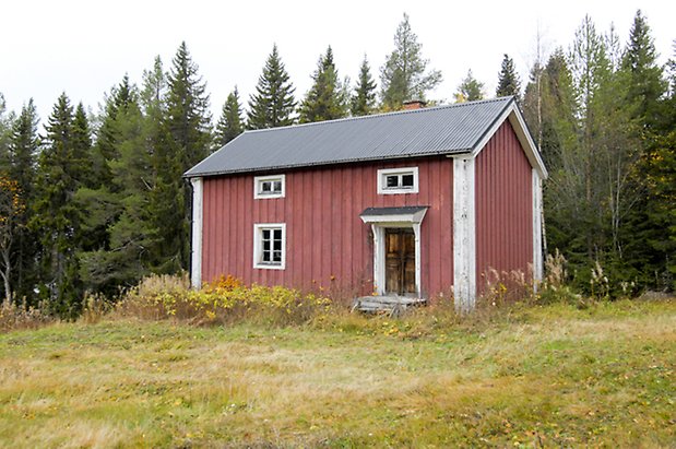 Grötom 1:27. Hus i två våningar i röd panel med vita detaljer, brun dubbeldörr och fönster med vita spröjs.