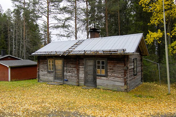 Häggesta 1:63. Hus i grått timmer med fönster med spröjs, två dörrar i svart.