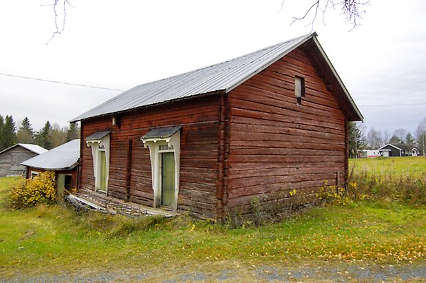 Häggesta 1:108. Röd timrad byggnad med två gröna dörrar.