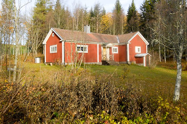 Storhögen 8:1. Hus i röd panel med vita detaljer, byggd i vinkel, fönster med vita spröjs, förstukvist och gul dörr. Källarnedgång med svart port.