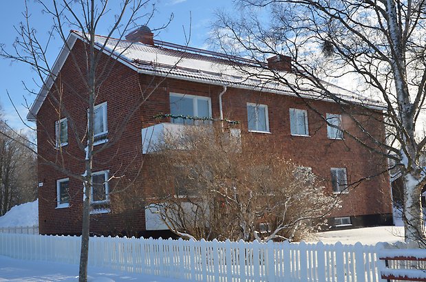 Brudsporren 8. Flerbostadshus i brunt tegel, i två våningar med vita fönster och två vita balkonger.