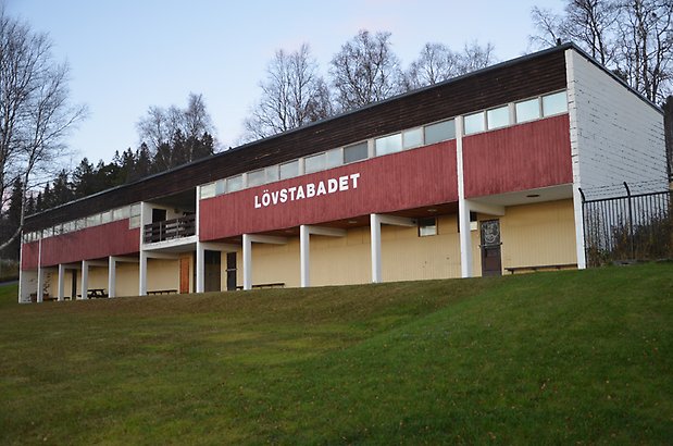 Frösö Berge 21-212. Byggnad i vitt tegel, röd och brun panel och gul puts. På fasaden står det Lövstabadet.