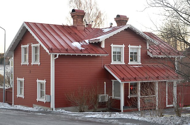 Smeden 5. Villa i röd, liggande panel med vita fönster med spörjs och rött plåttak. 