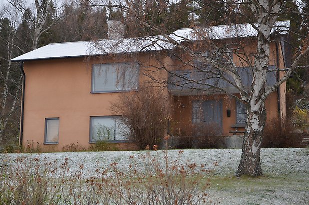 Berghem 2. Villa i brun puts med gröna fönster och grå balkong. 