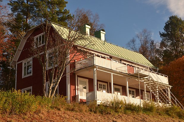 Frösö Berge 21-212. Villa i röd panel med vita fönster med spröjs och vita balkonger som går längs långsidan, Grönt plåttak. 