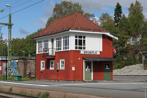 Brunflo-Viken 2:10. Byggnad i röd panel på nedervåningen och vit panel på övervåningen. Vita fönster med spröjs och gröna dörrar. Balkong med smidesräcke.