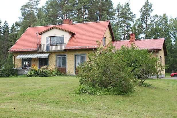 Häggenås Prästbord 1:16. Villa i gult tegel med grå detaljer och grå fönster med bruna spröjs, bruna dörrar.