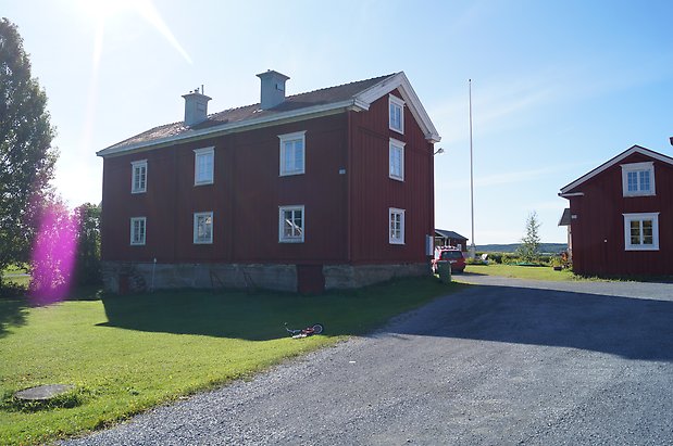 Torvalla 3:4. Hus i tre våningar i röd panel med vita detaljer, fönster med vita spröjs, två skorstenar.