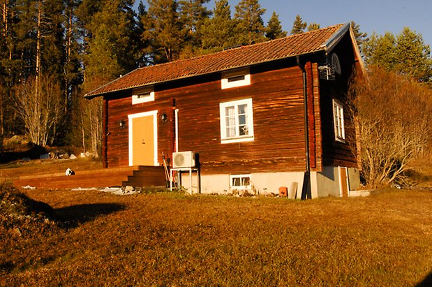 Lockne-Berge 1:7. Rött, timrat hus i två våningar med stengrund, liten trapp upp till en gul dubbeldörr, fönster med vita spröjs.