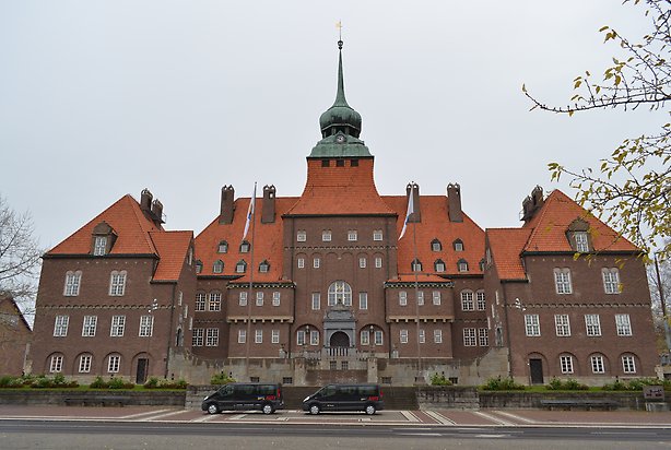 Östersunds rådhus. Byggnad i brunt tegel, orange tak med ett torn i grönt.