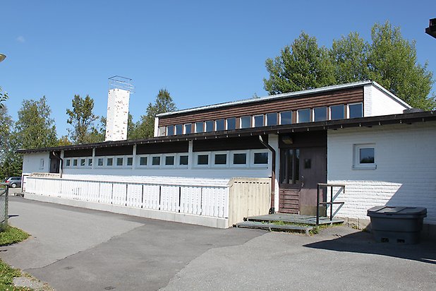 Näs-åsen 3:11. Byggnad i vitt mexitegel och svart panel med sluttande tak och vita fönster och vit skorsten.