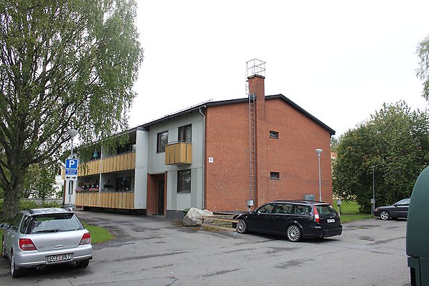 Söre 5:22. Flerbostadshus i två våningar i brunt tegel och betong med gula balkonger.