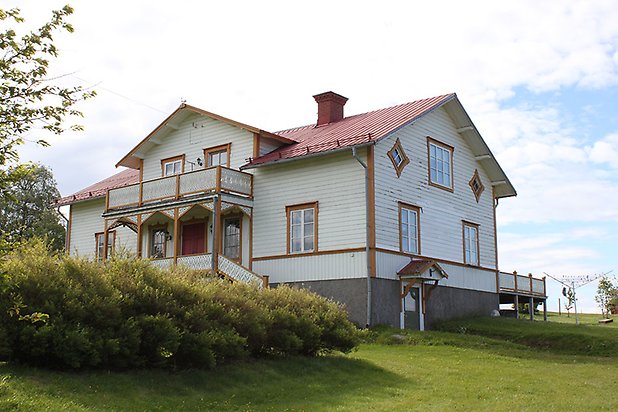 Orrviken 6:1. Villa i vit liggande panel med gula detaljer och vita fönster med spröjs. Rött plåttak. Förstukvist och balkong.