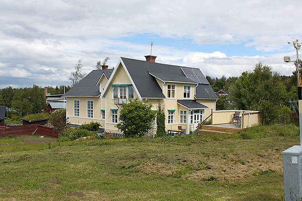 Orrviken 6:8. Villa i gul, liggande panel med vita fönster med spröjs.