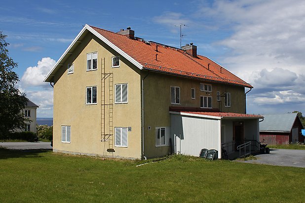 Orrviken 6:41. Byggnad i grön puts med vita fönster och tillbyggnad i vit panel.